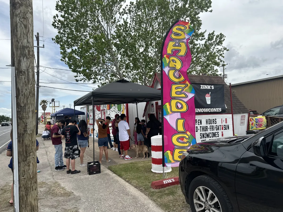A line of customers outside Zink's on a sunny afternoon