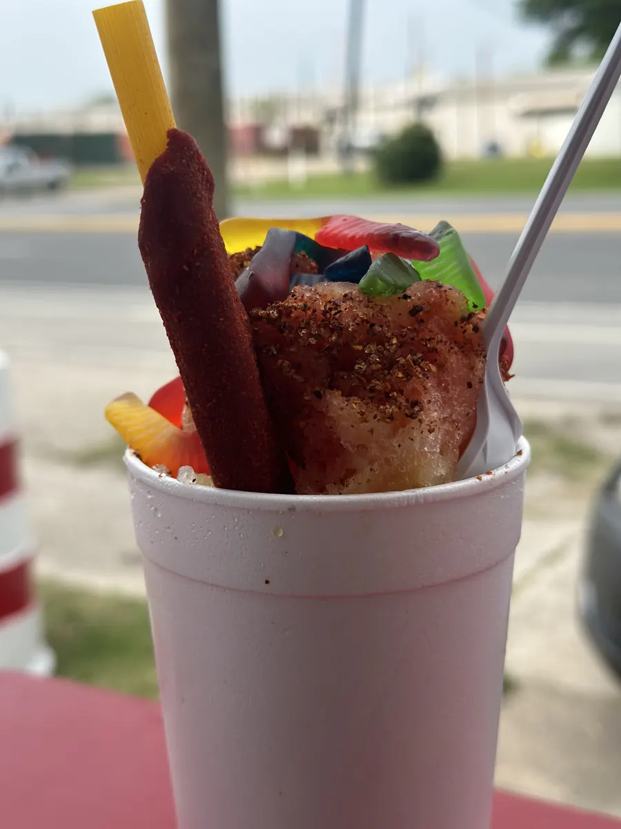 A loaded chamoy snow cone with a tamarindo straw and gummies